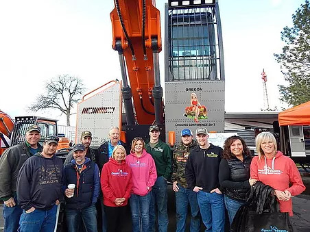 Cascade Trader Inc. Service Department team posing in front of an excavator